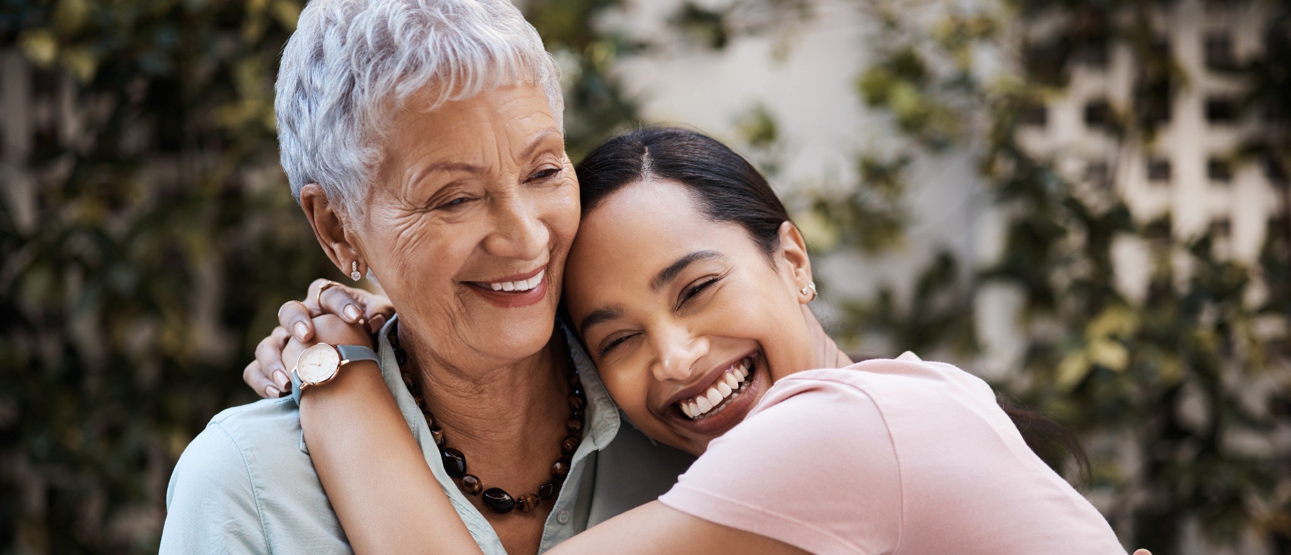 A senior mom is hugged by her adult daughter.